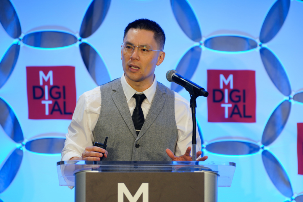 Eric So, IDE Research Lead and MIT Sloan Professor, speaking at a podium